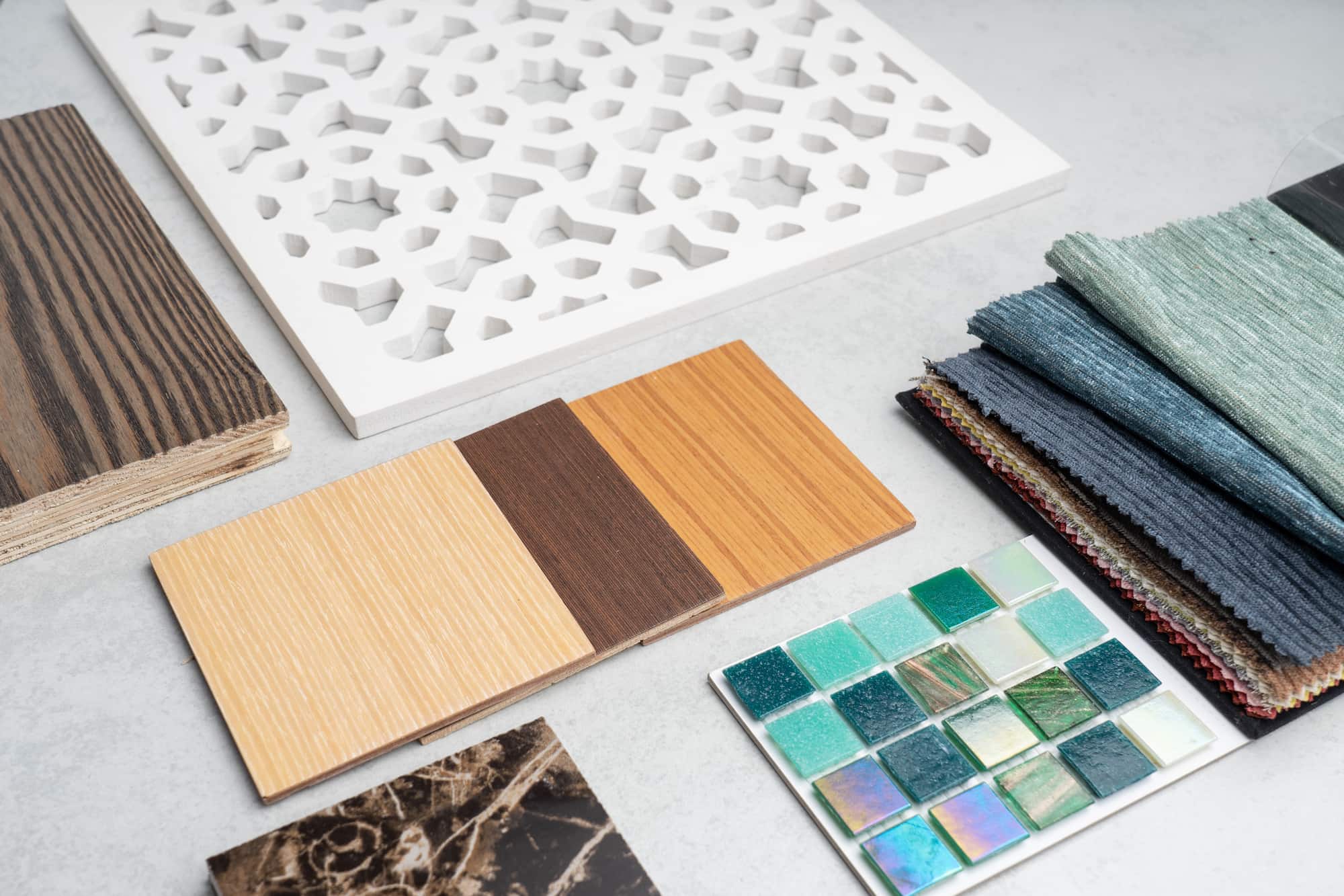 Interior design material samples including wood finishes, decorative panels, fabric swatches and mosaic tiles used for bespoke home renovation projects by Sunny Build.