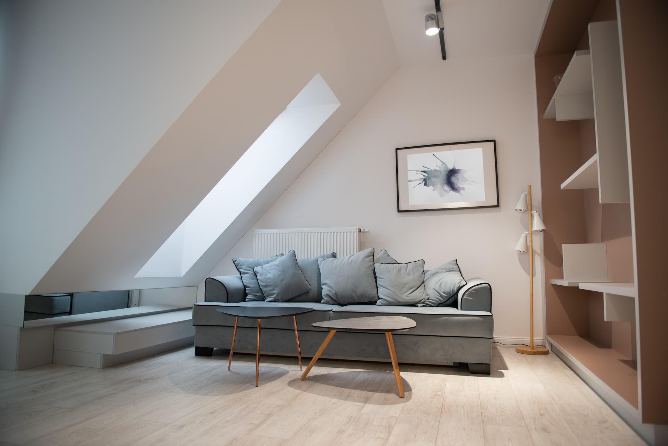 Completed loft conversion with rooflight window, bespoke shelving, modern furnishings and a bright, comfortable living area created by Sunny Build in Kingston.