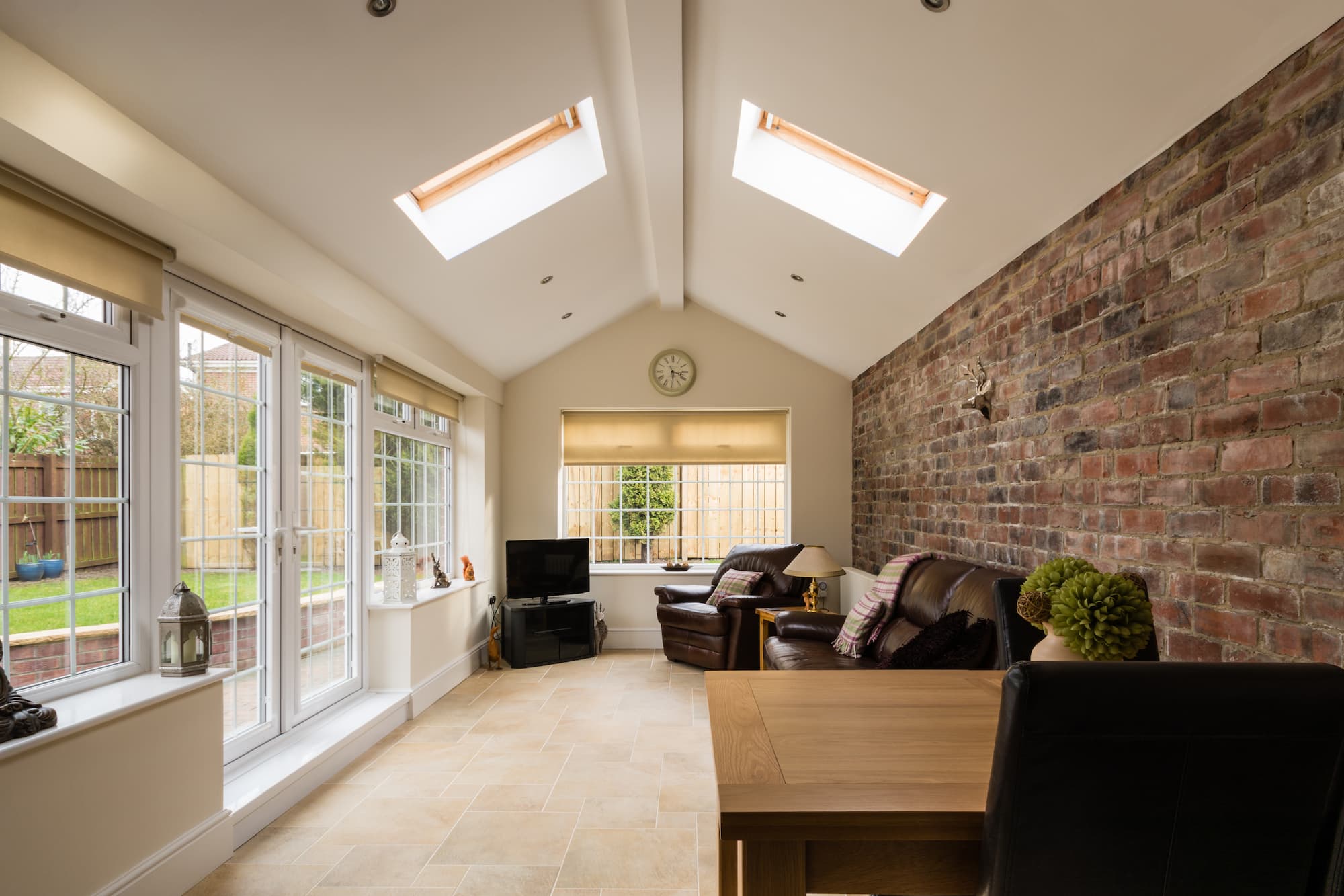 Rear house extension with vaulted ceiling, rooflight windows, exposed brick feature wall and bright open-plan living space completed by Sunny Build in South West London.